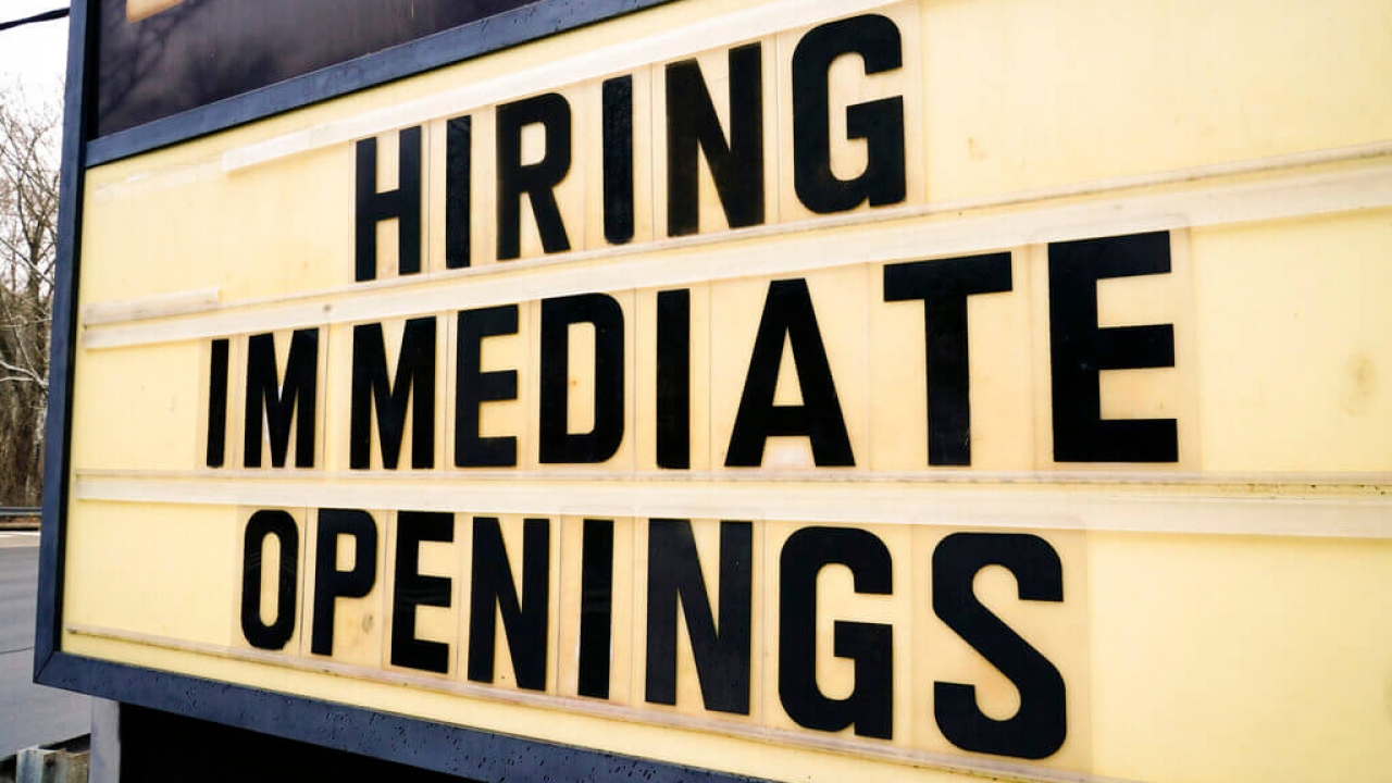 A hiring sign is posted outside a business.