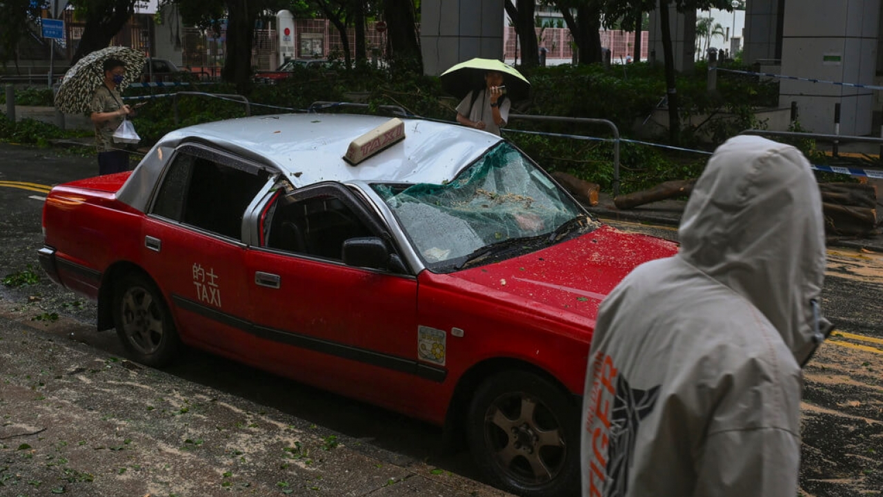 Residents look at a taxi damaged by Typhoon Saola in Chai Wan, Hong Kong.