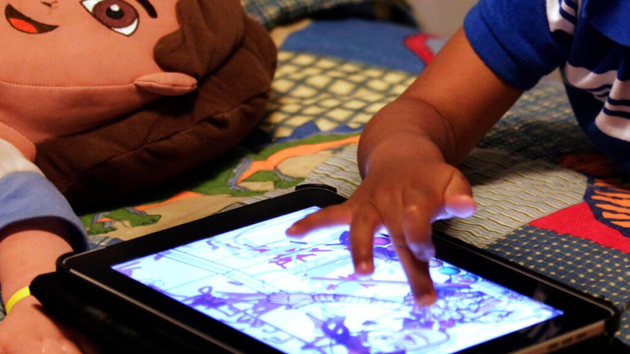A child plays with an iPad in his bedroom.