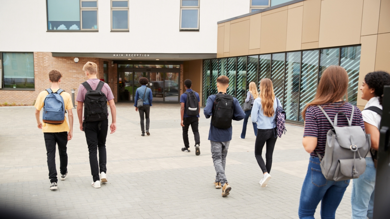 Teens enter a school building.