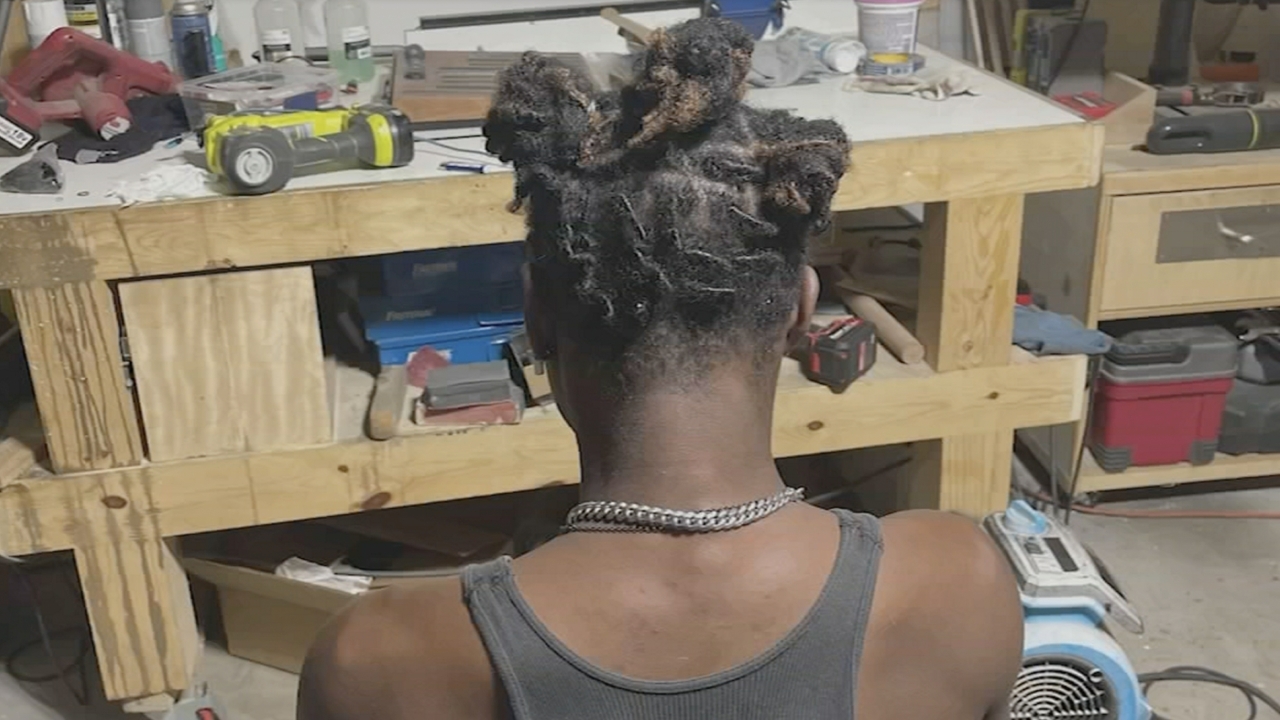 The back of a student's head shows his loc'd hair tied back.