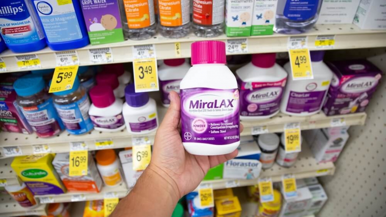 A person holding a bottle of MiraLax, popular generic laxative.