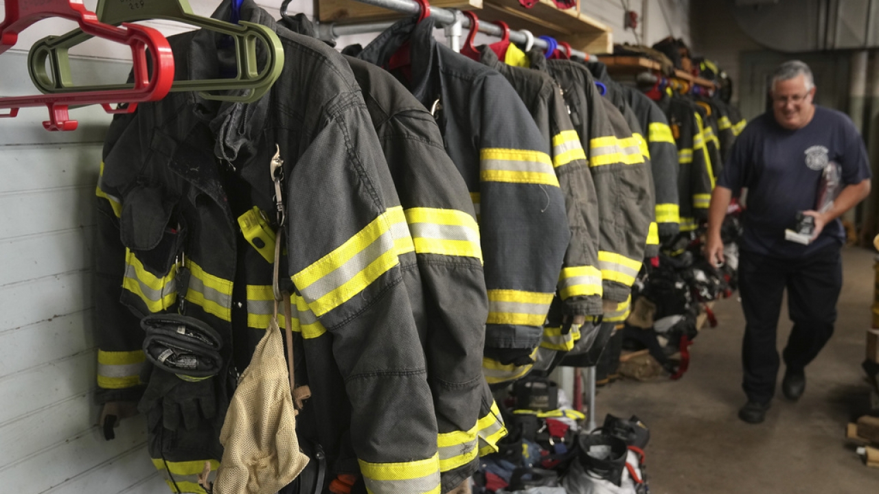 Firefighter protective gear hangs on a rod in Massachusetts firehouse.