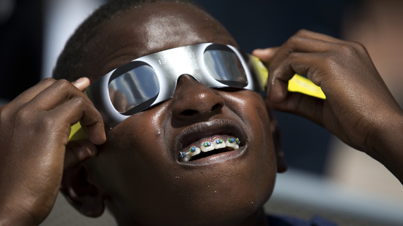 A boy wears a pair of special solar eclipse glasses up to his eyes.