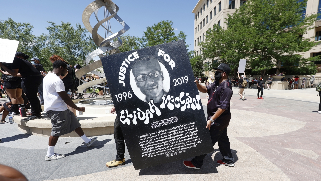 Demonstrators carry a giant placard during a rally and march over the death of Elijah McClain.