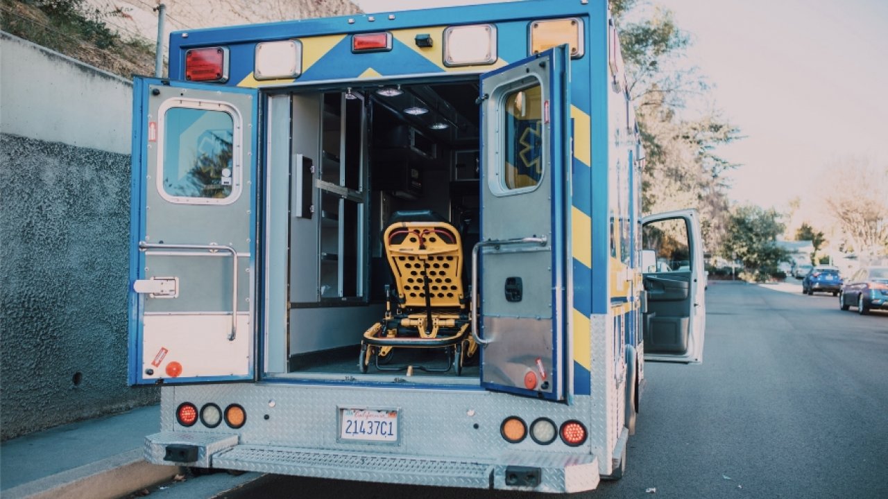 Back doors of an ambulance are open, revealing a stretcher