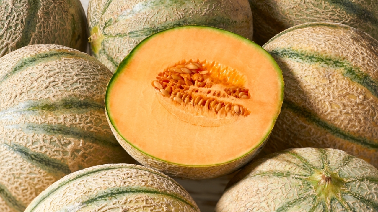 A bunch of cantaloupe melons with one sliced open.