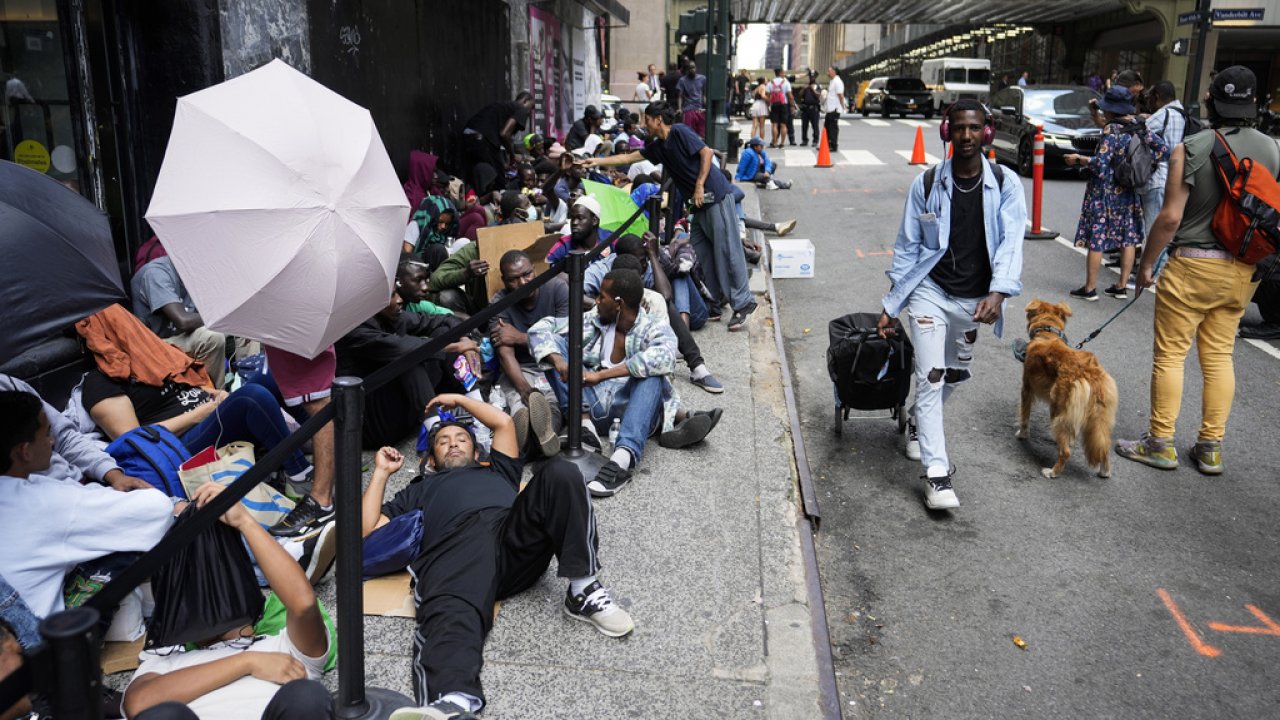 Migrants sit in a queue outside of The Roosevelt Hotel in New York City.