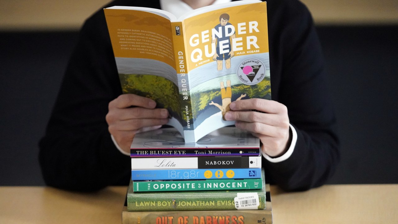 An individual poses with books that have been the subject of complaints from parents on Dec. 16, 2021, in Salt Lake City.