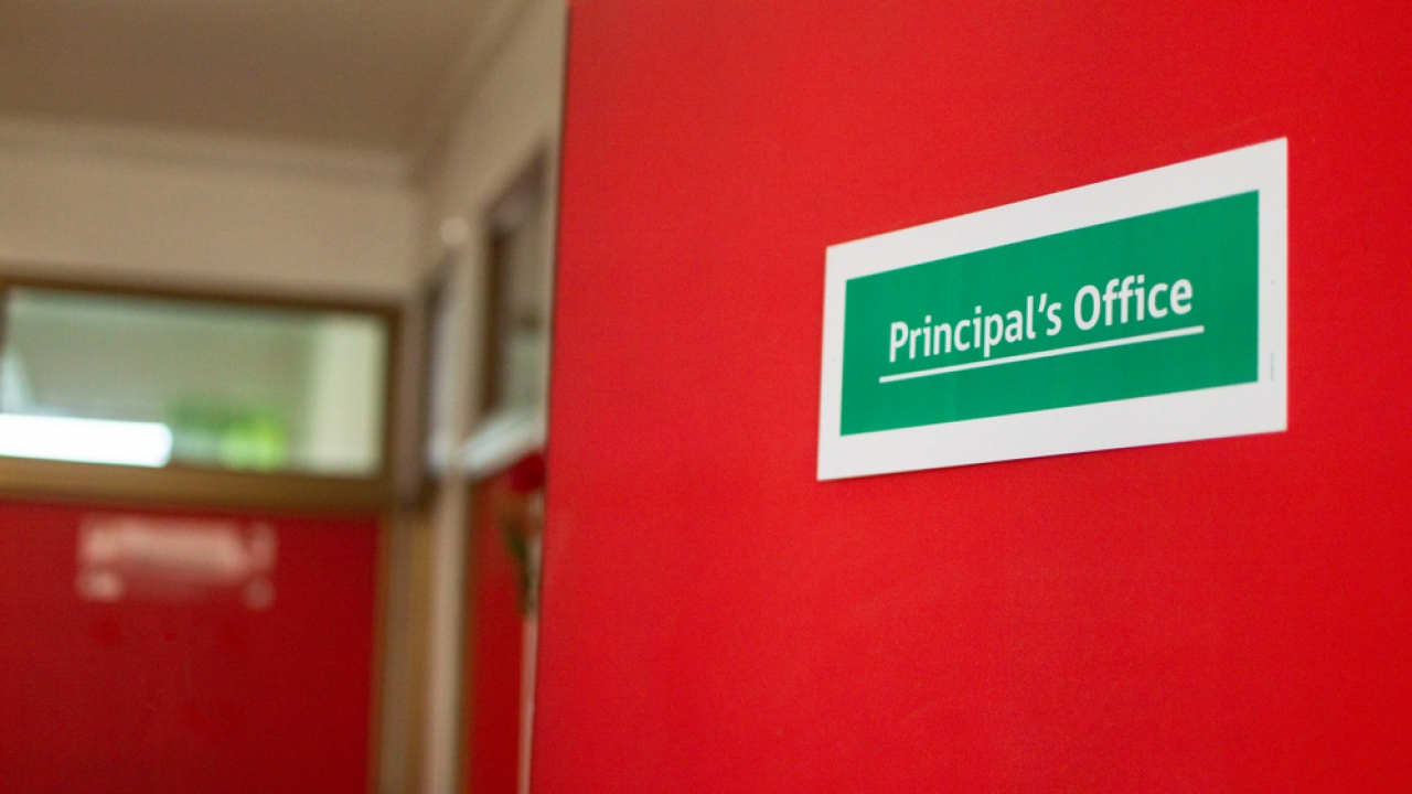 Red door with a green sign that says Principal's Office
