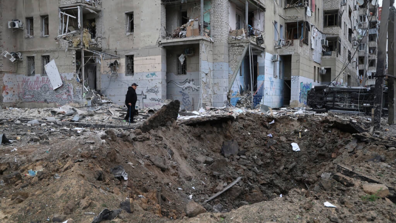 A local resident passes by a crater caused by a Russian rocket attack in central Kharkiv, Ukraine.