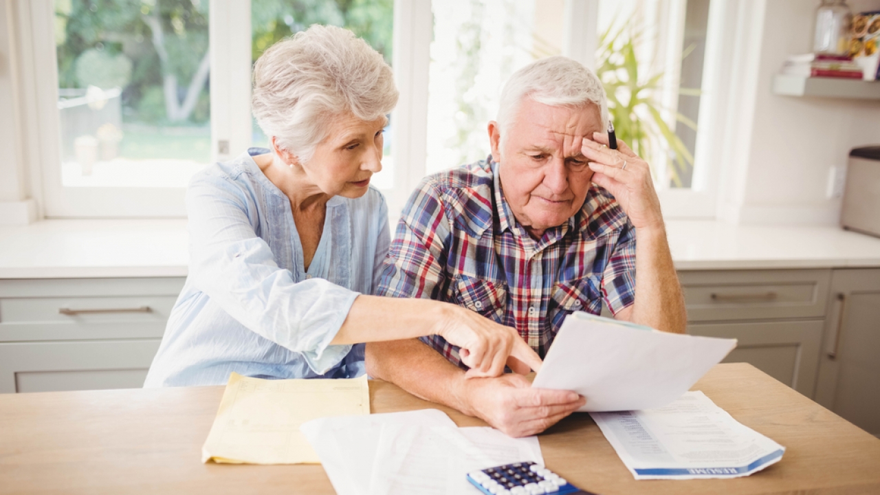 Senior couple looking at their bills with worried expressions