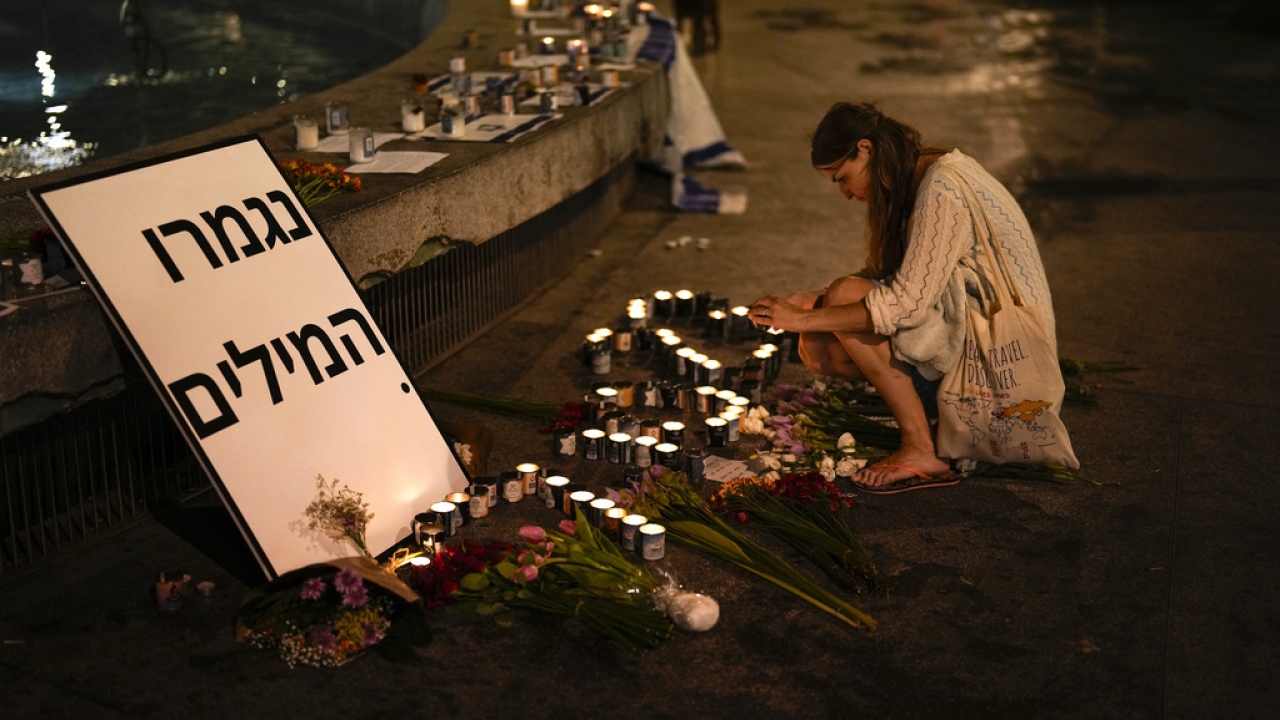 A woman lights candles in honor of victims of the Hamas attacks during a vigil in Tel Aviv, Israel.