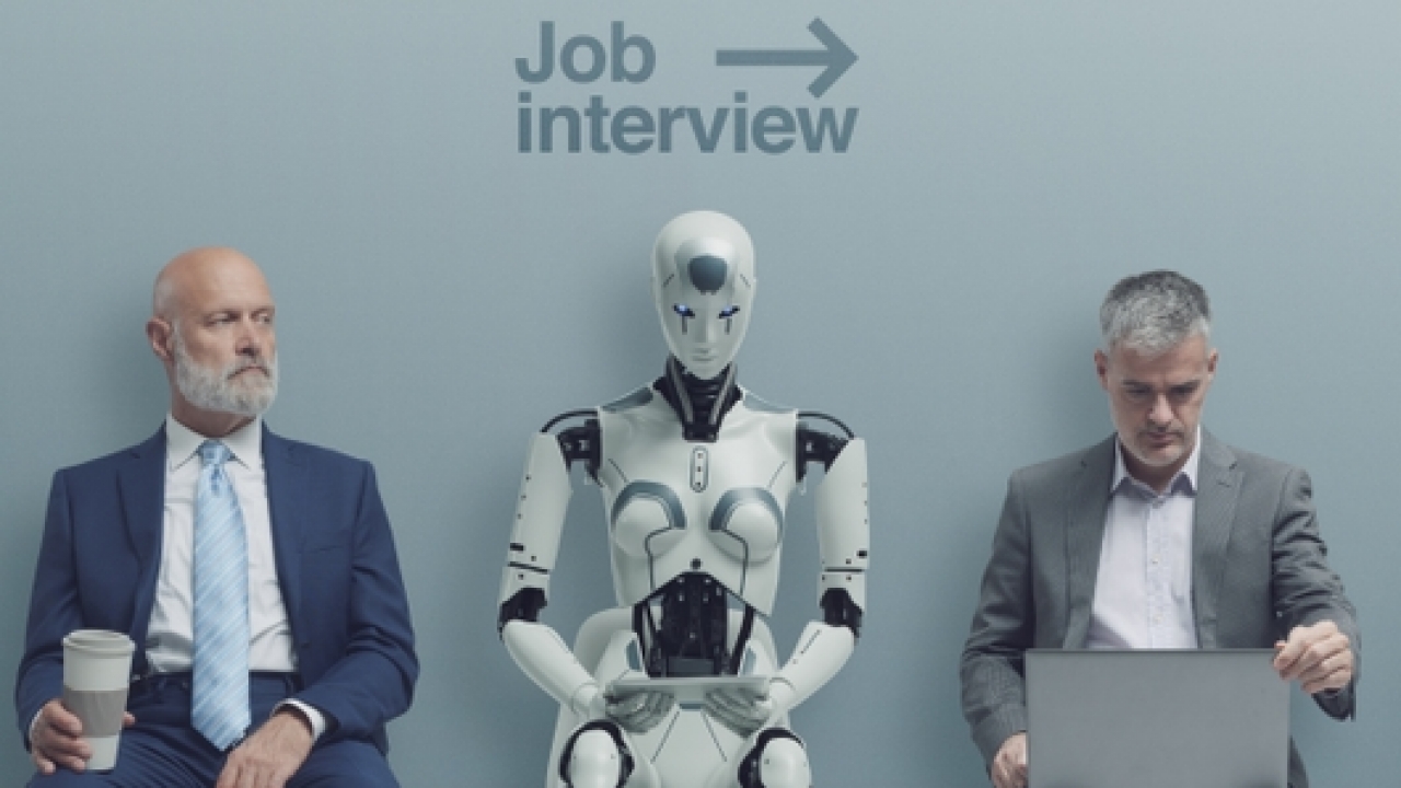 Stock photo of a robot sitting amongst humans, waiting for a job interview.