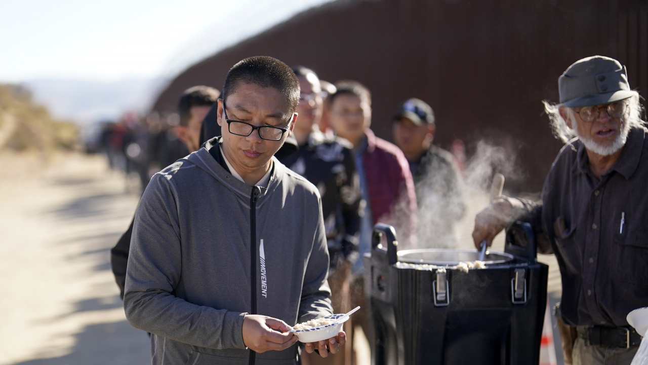 A man from China gets a bowl of oatmeal from a volunteer as he waits with others for processing to apply for asylum.