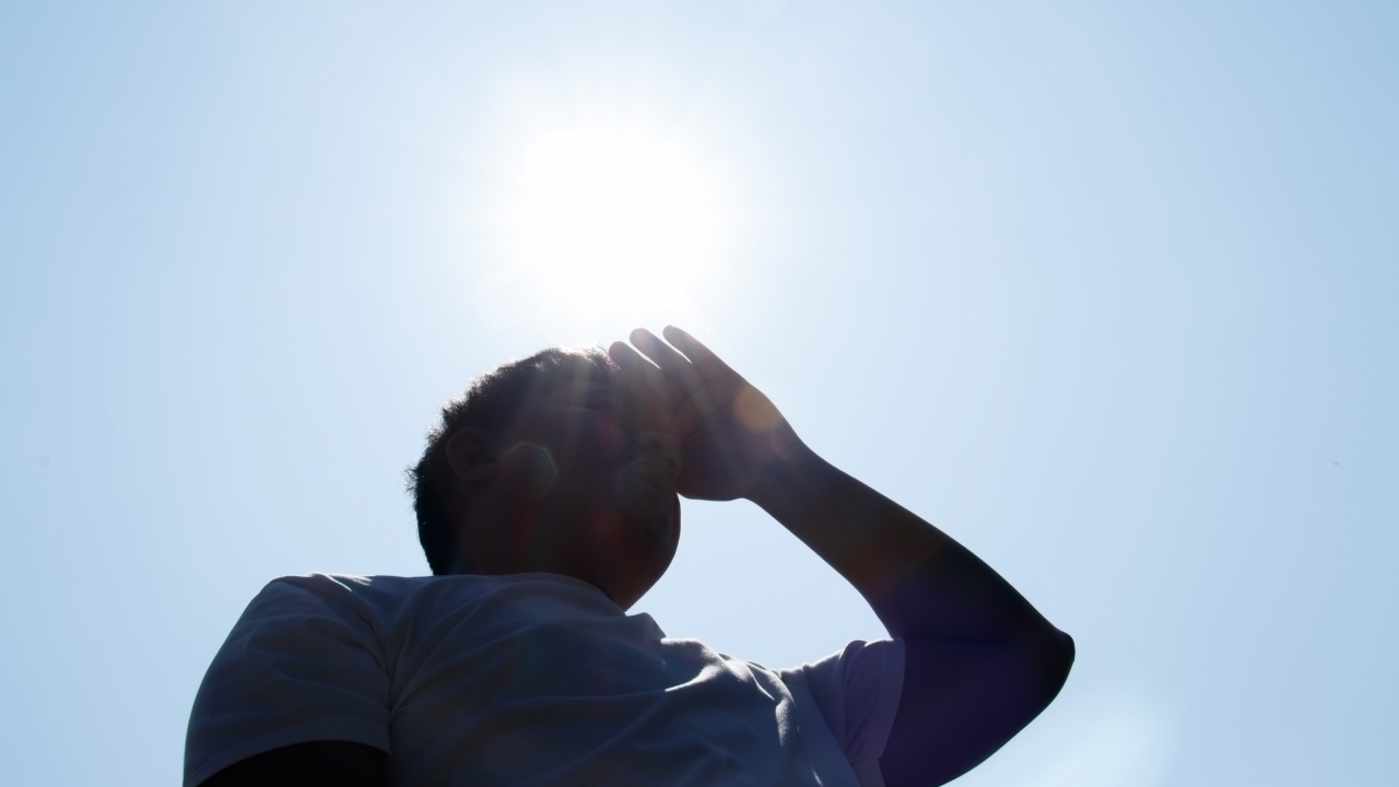 Person covers face with hand under hot sun
