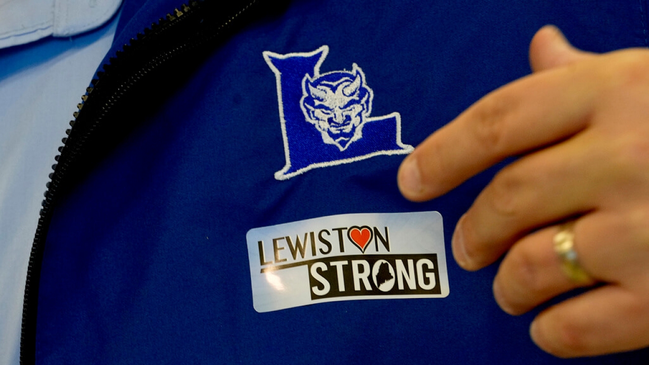 School superintendent applies a Lewiston Strong sticker to his jacket as high school students return after