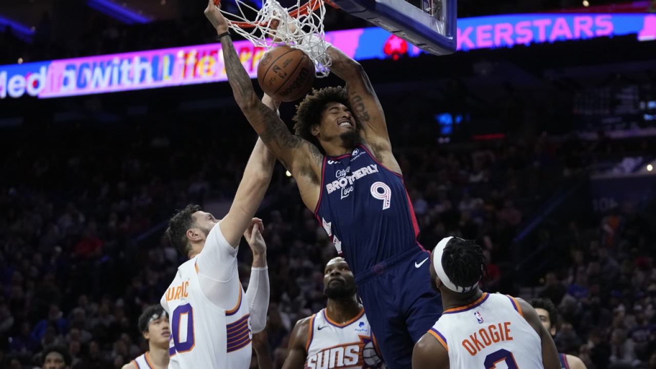 Philadelphia 76ers' Kelly Oubre Jr. dunks past opposing players during a game.