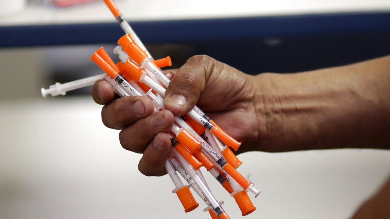 File photo of a person holding used needles.