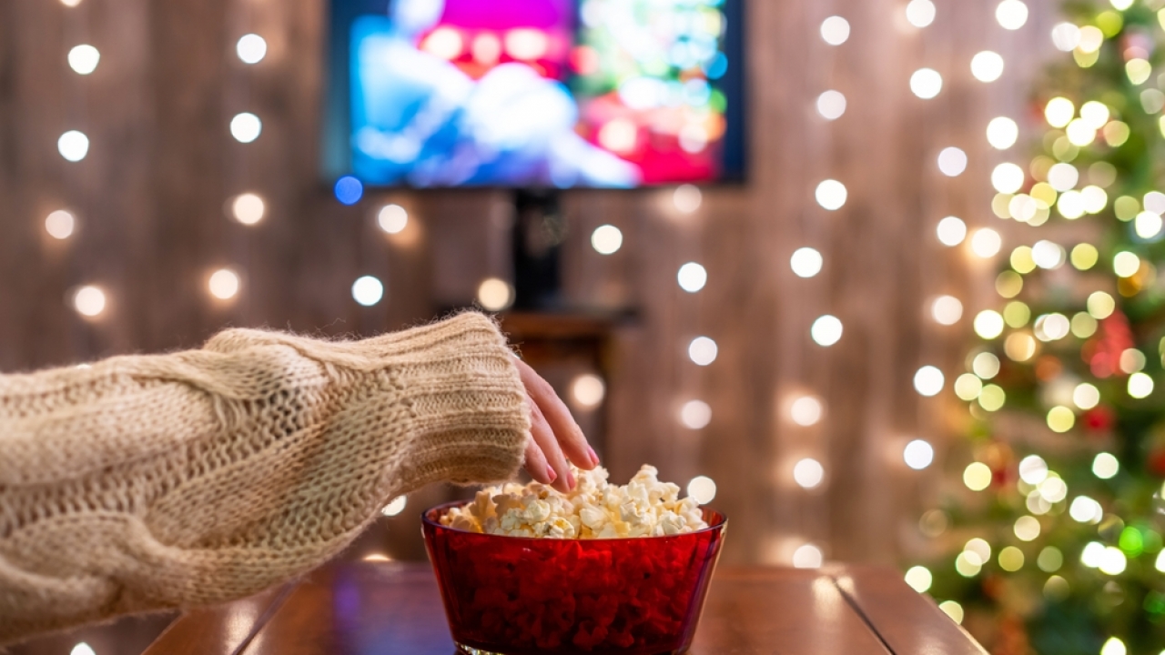 Woman watching tv and eating popcorn with holiday decorations