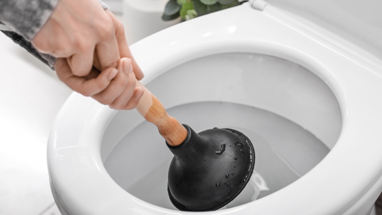 Person uses a plunger on a toilet.
