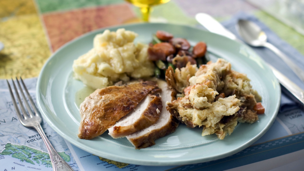 A plate of roasted turkey and gravy, stuffing, mashed potatoes, and glazed carrots.