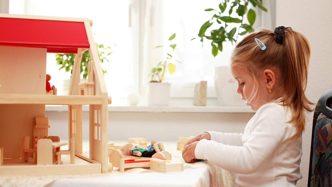 A girl plays with a dollhouse.