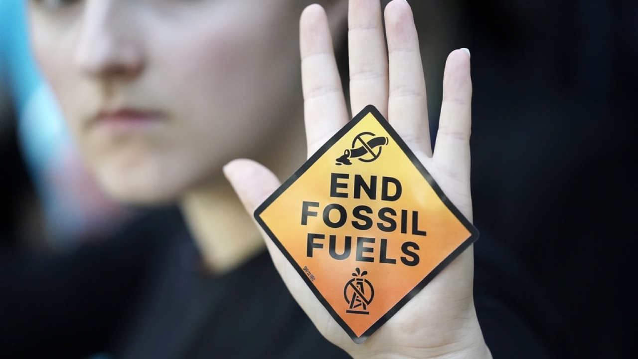A demonstrator displays a sign reading "end fossil fuels" at the COP28 U.N. Climate Summit in Dubai