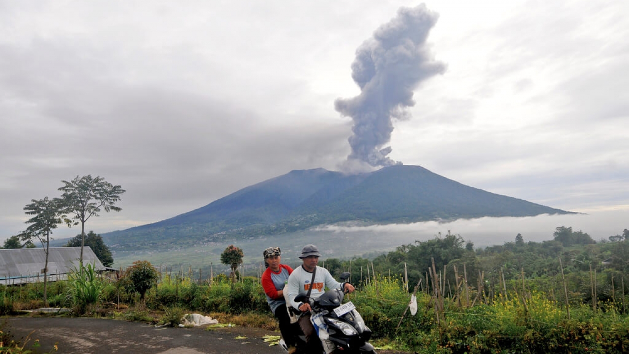 Motorists ride past by as Mount Marapi spews volcanic materials during its eruption in Agam, West Sumatra, Indonesia.