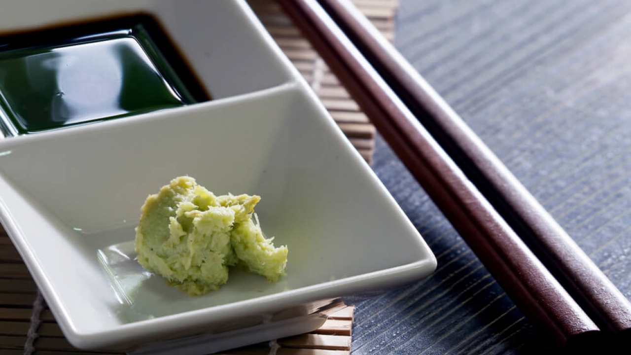 Wasabi served on a plate next to soy sauce.