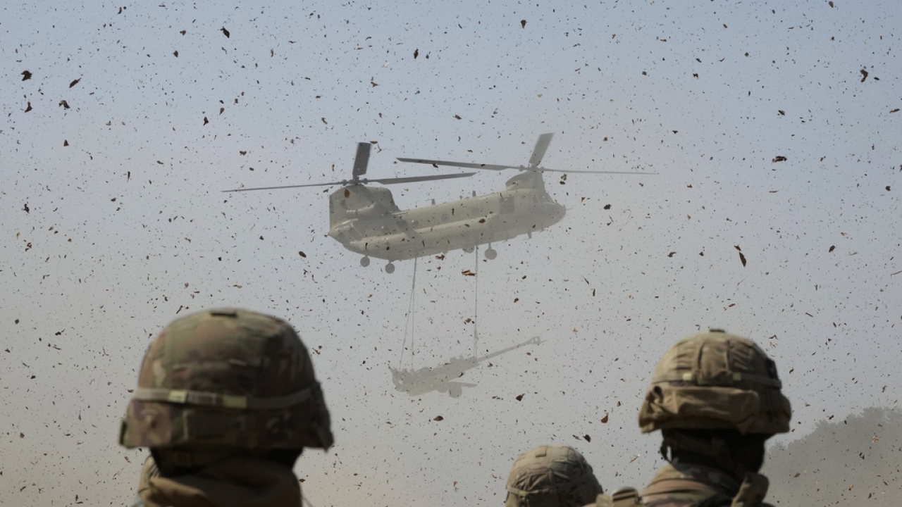 A U.S Army CH-47 Chinook helicopter transports a M777 howitzer.