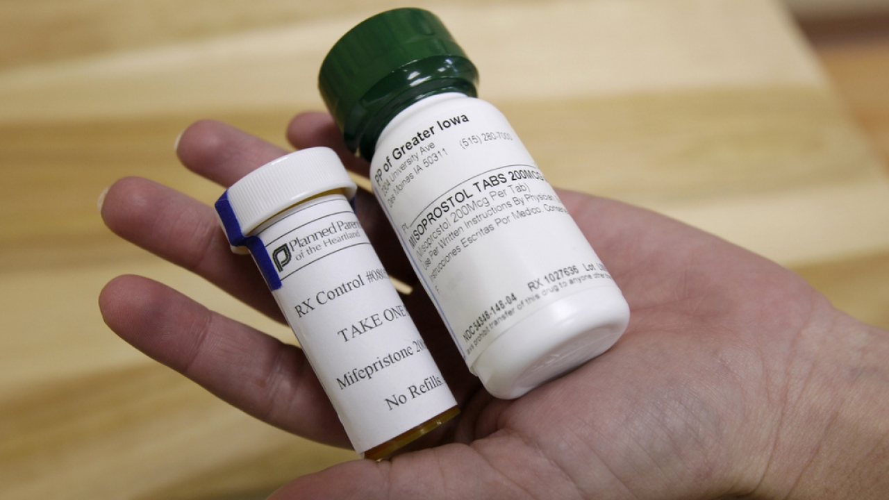 A hand holds two bottles of abortion pills at a clinic