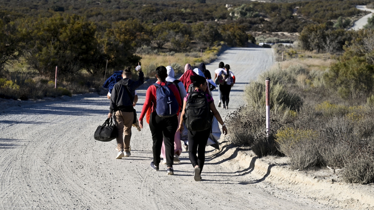 Asylum-seekers walk to a U.S. Border Patrol van after crossing the nearby border with Mexico