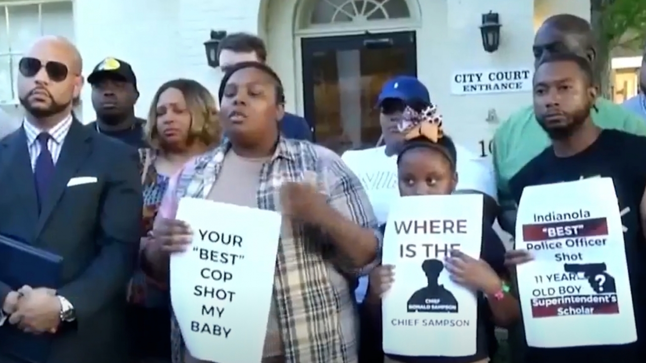 The family of the boy shot holds signs calling for justice against an officer who shot an 11-year-old.
