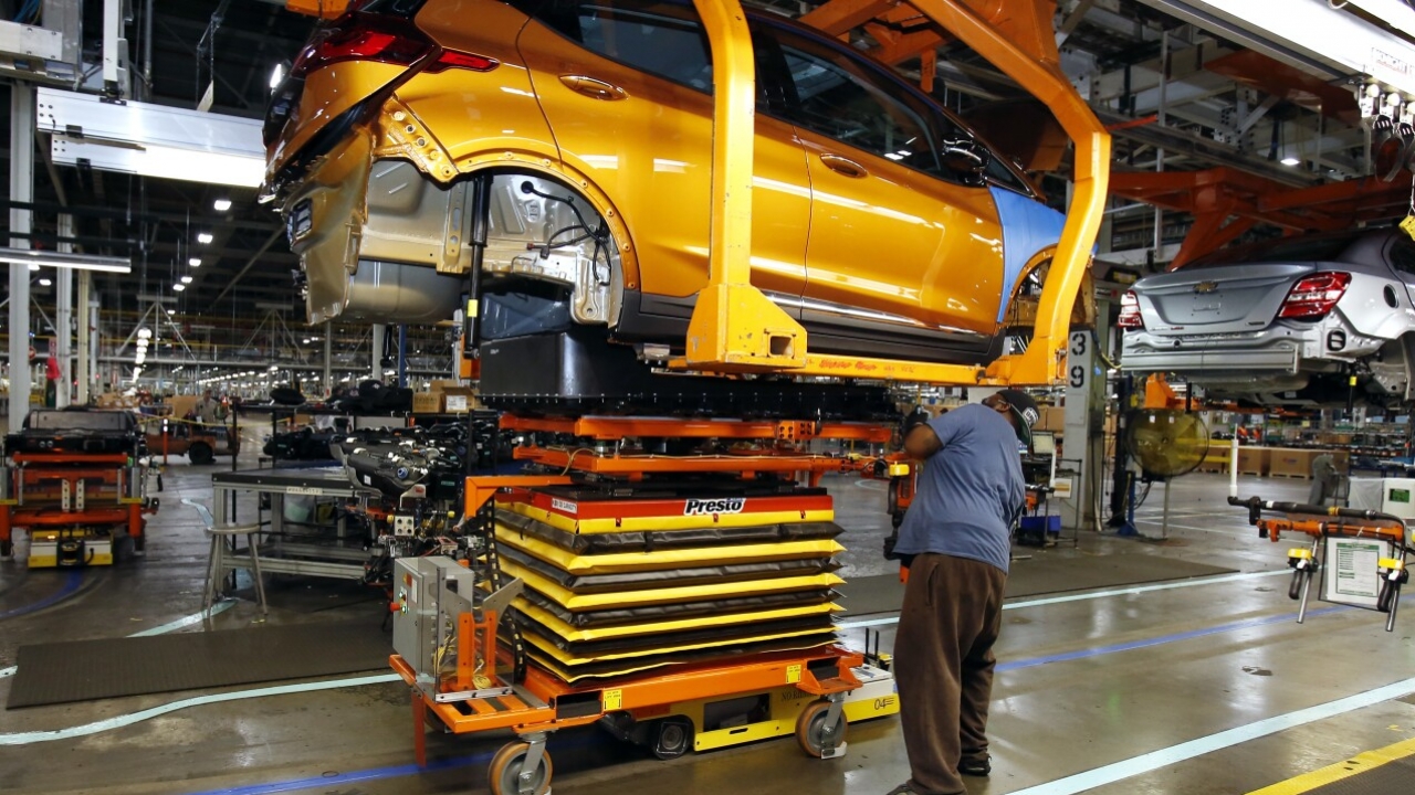 A General Motors employee working under a lifted vehicle