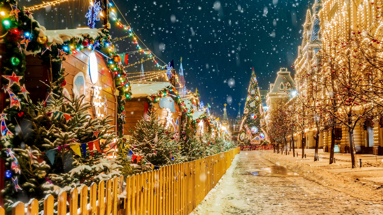 Town adorned with Christmas lights and decor during snowfall