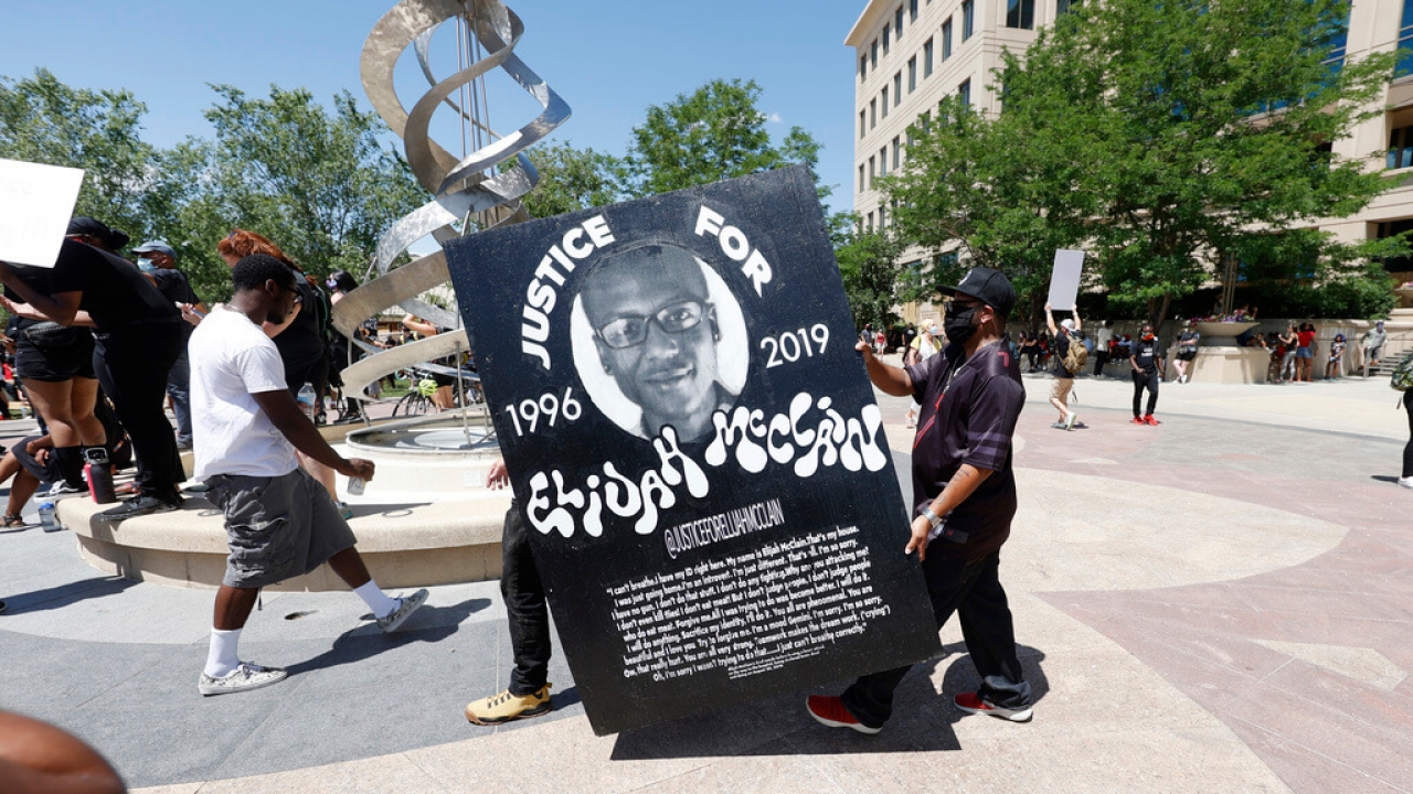 Demonstrators carry a placard memorializing Elijah McClain