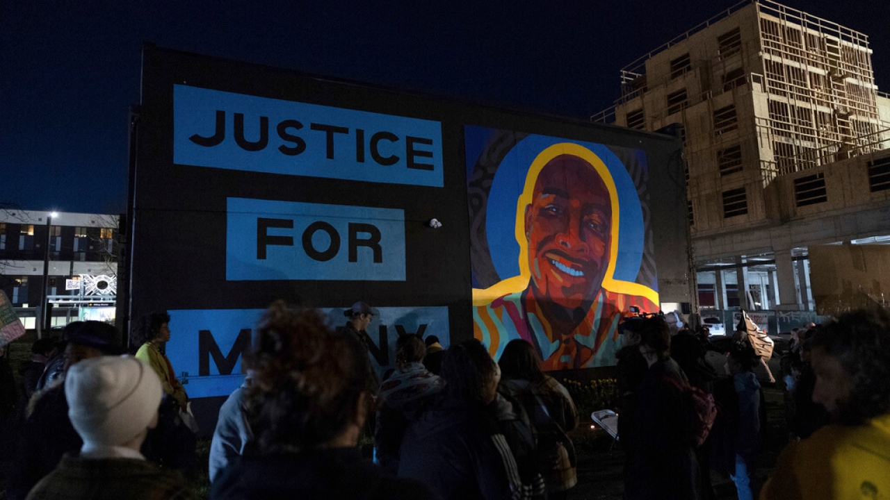 Protesters rally in front of a sign calling for justice for Manny Ellis