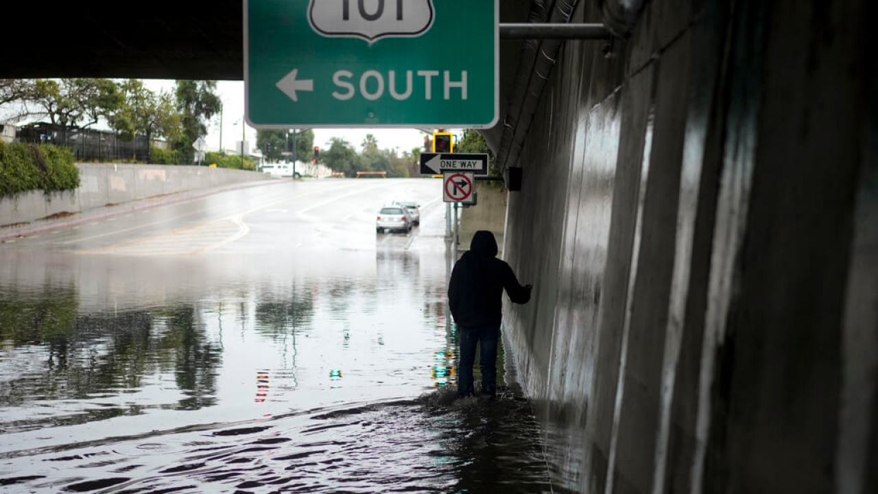 A pedestrian walks under a flooded freeway underpass in Santa Barbara, California