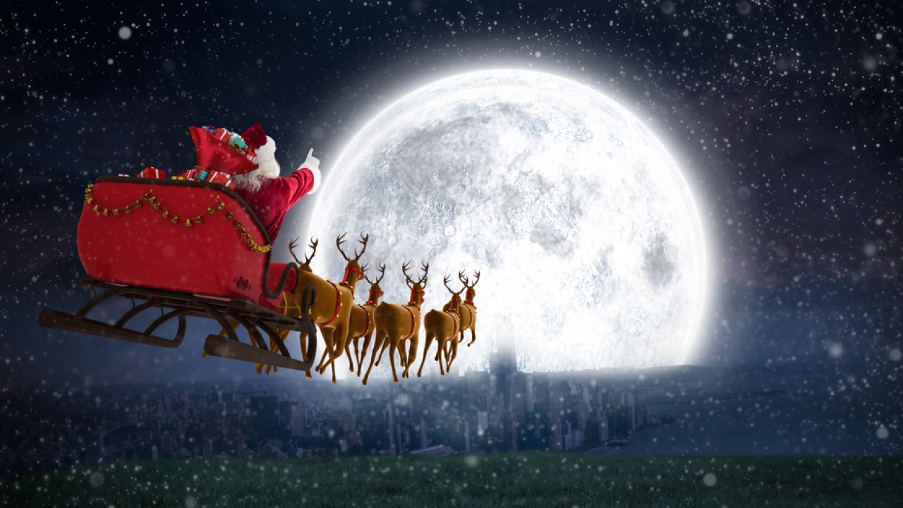 Santa with his reindeer in front of a moon