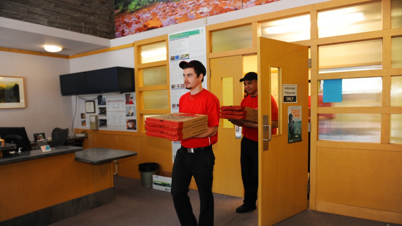 Pizza Hut delivery drivers arrive at an office with pizzas.