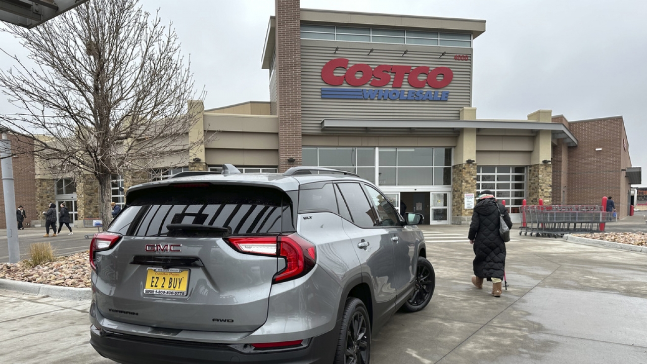 A shopper passes by a 2023 GMC Terrain sports-utility vehicle on display outside a Costco warehouse.