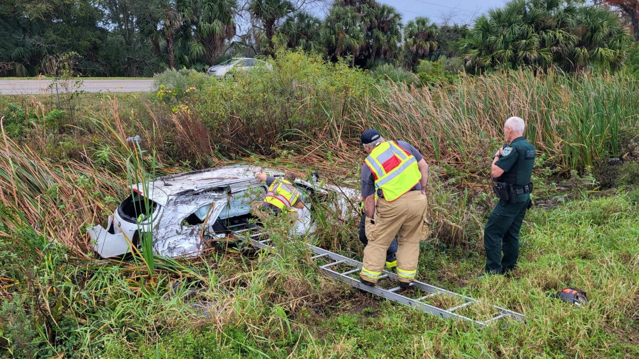 First responders work to remove presents from a car in a ditch.
