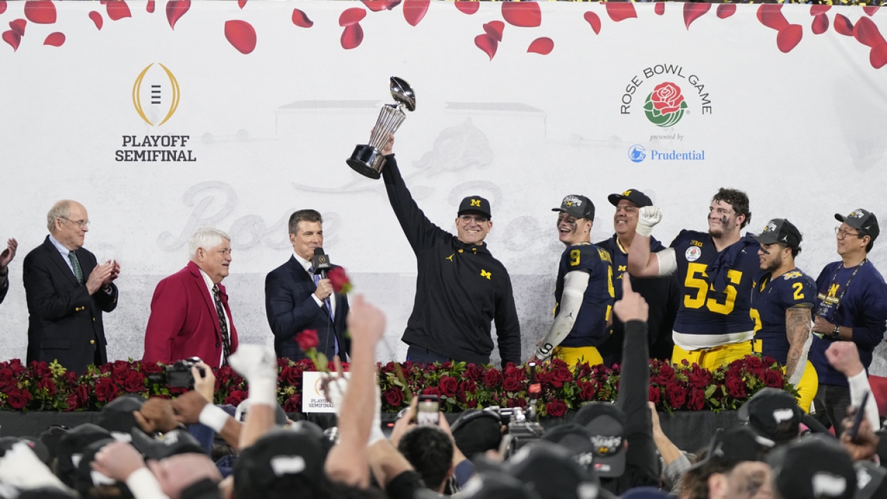 Michigan head coach Jim Harbaugh holds the winner's trophy after a win over Alabama in the Rose Bowl.