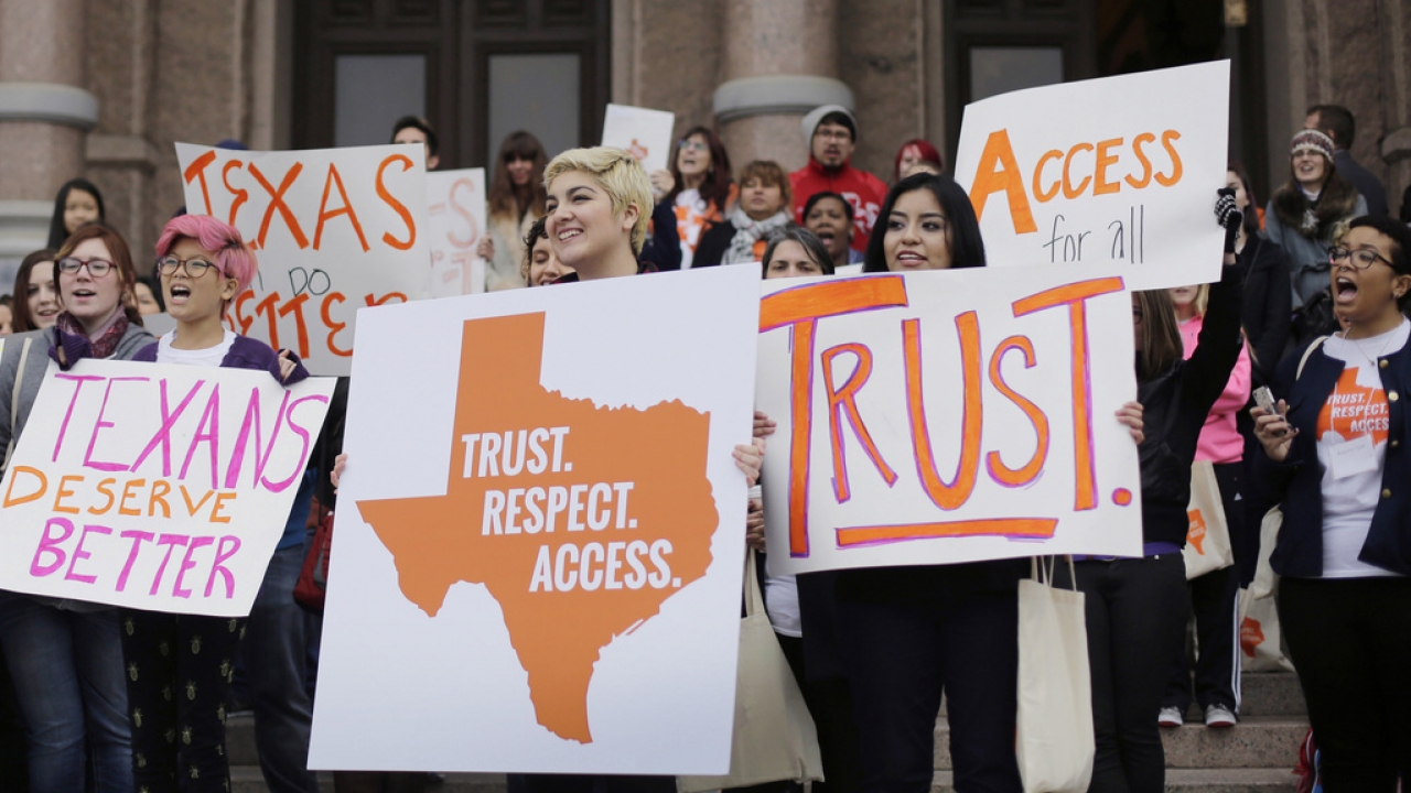 College students and abortion rights activists hold signs during a rally on the steps of the Texas Capitol.