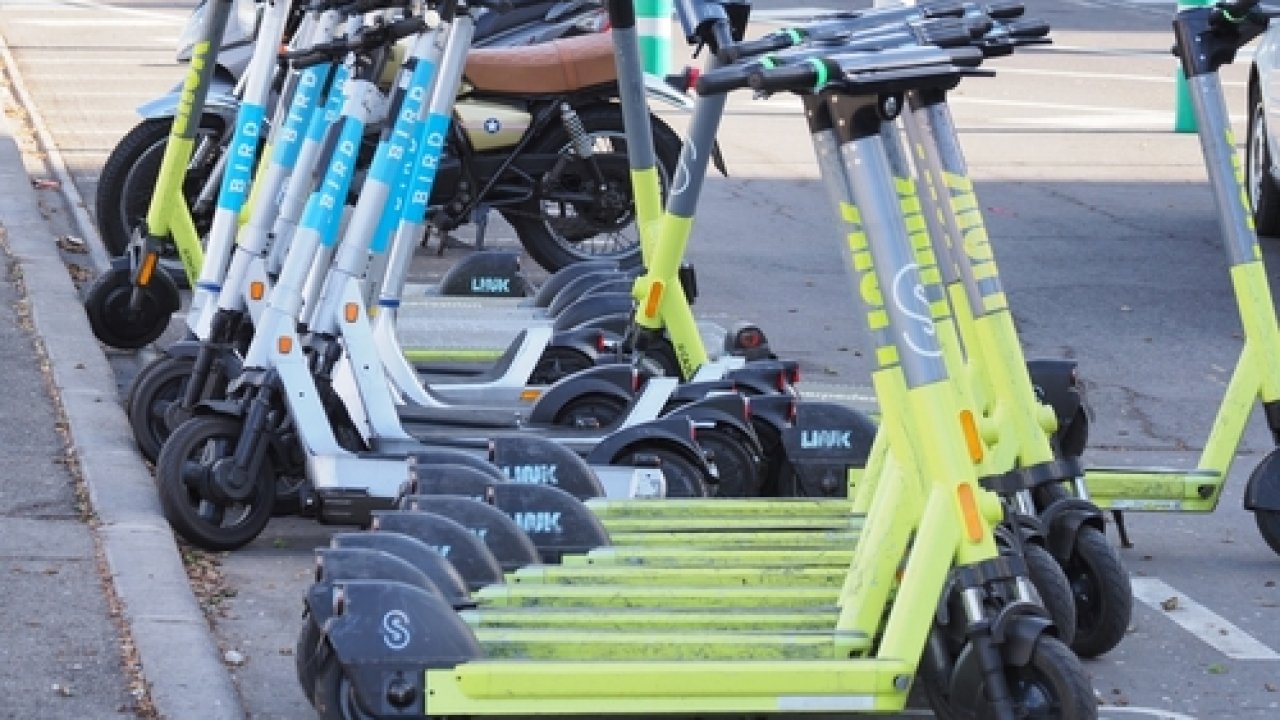 Link and Bird e-scooters parked near a sidewalk.