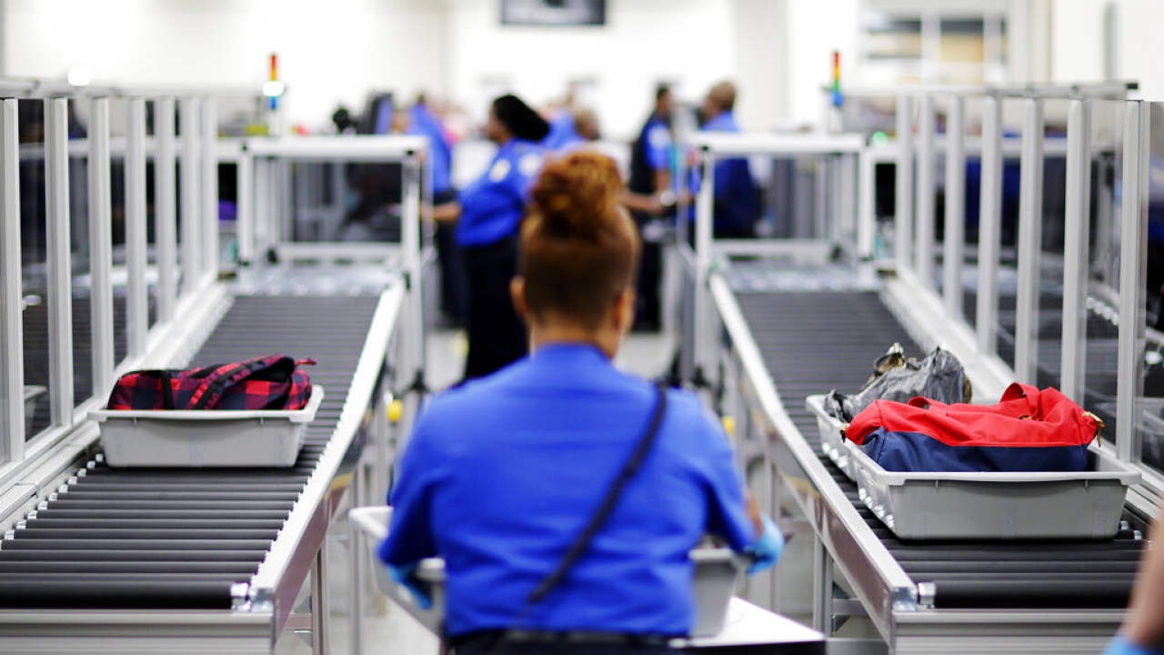 A TSA employee stands at the airport security checkpoint.