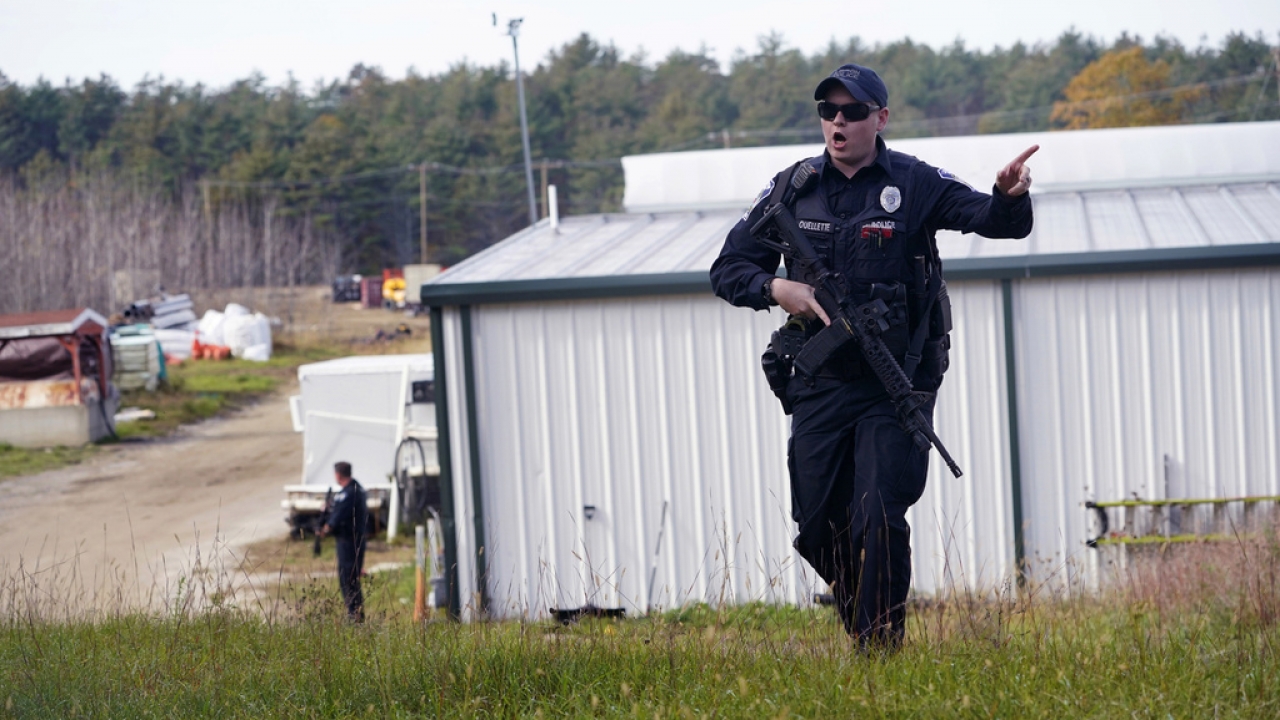 Police officer gives orders to the public during a manhunt for a mass shooter in Maine.