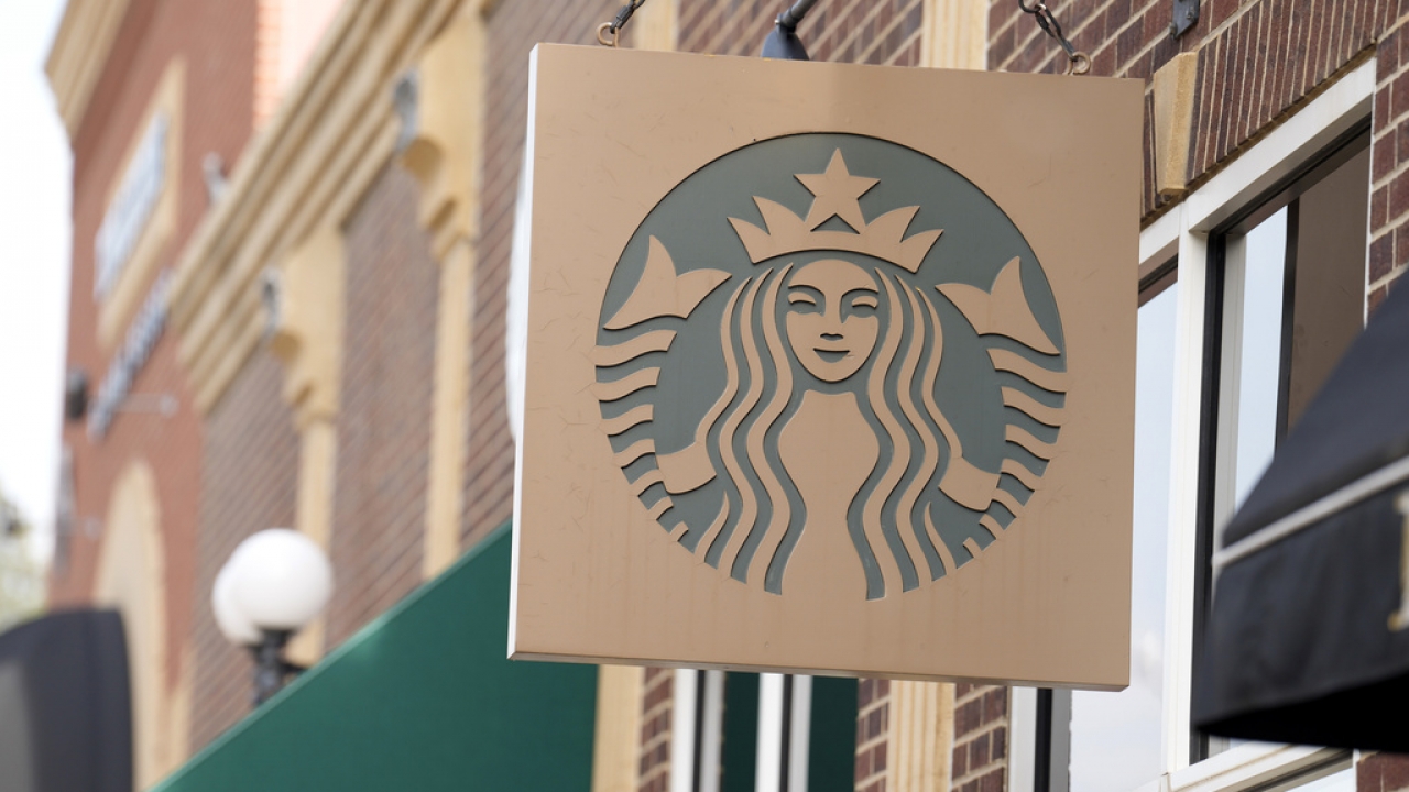 Starbucks sign hangs outside a coffee shop.