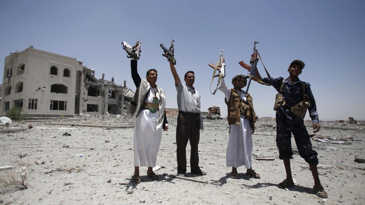 Shiite fighters, known as Houthis, hold up their weapons as they chant slogans at the residence of a military commander.